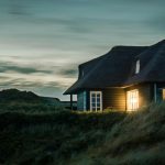 gray house with fireplace surrounded by grass under white and gray cloudy sky