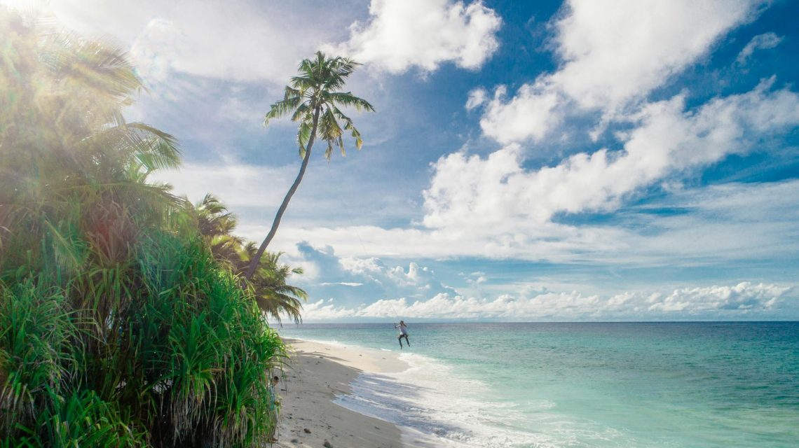 person running on seashore under white clouds