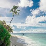 person running on seashore under white clouds