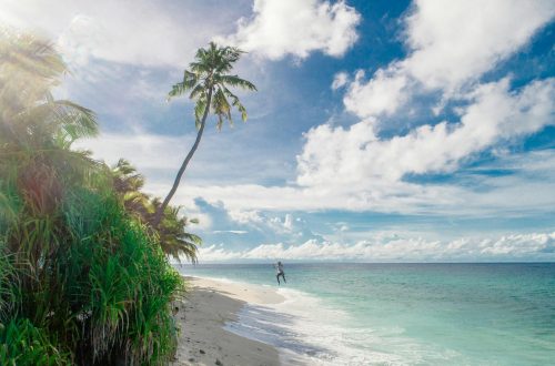 person running on seashore under white clouds