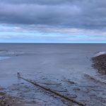 view of the beach and sea under a cloudy sky