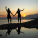 silhouette of two women standing on the beach during sunset