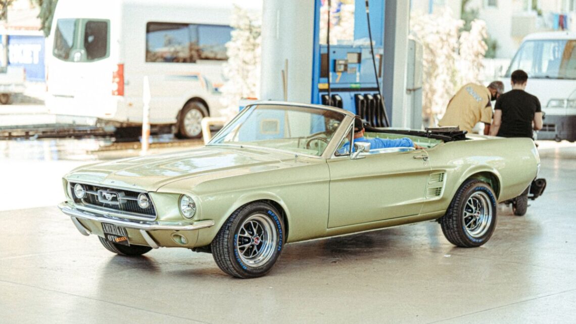 a vintage convertible car parked on the gasoline station